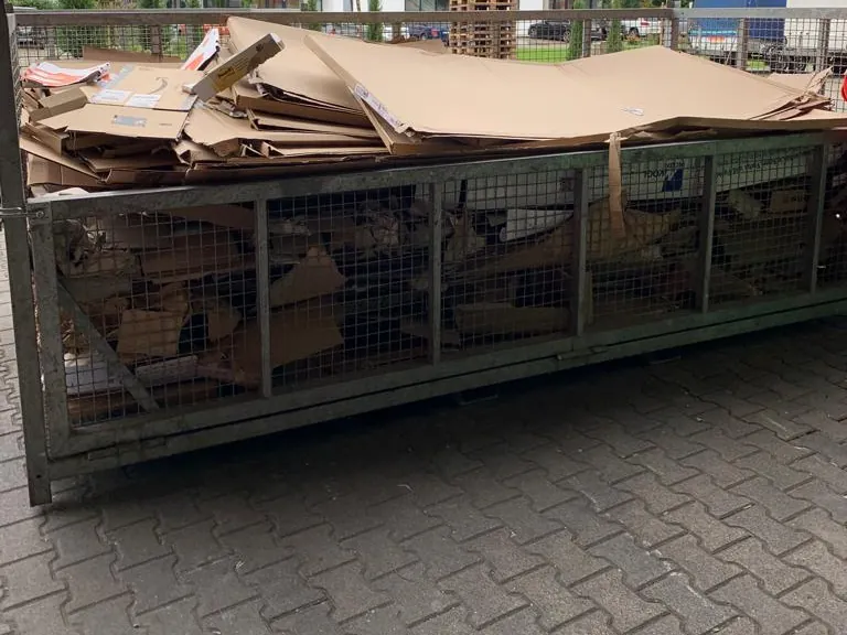Gitterbox mit getrennt gesammelter Pappe im Freien
